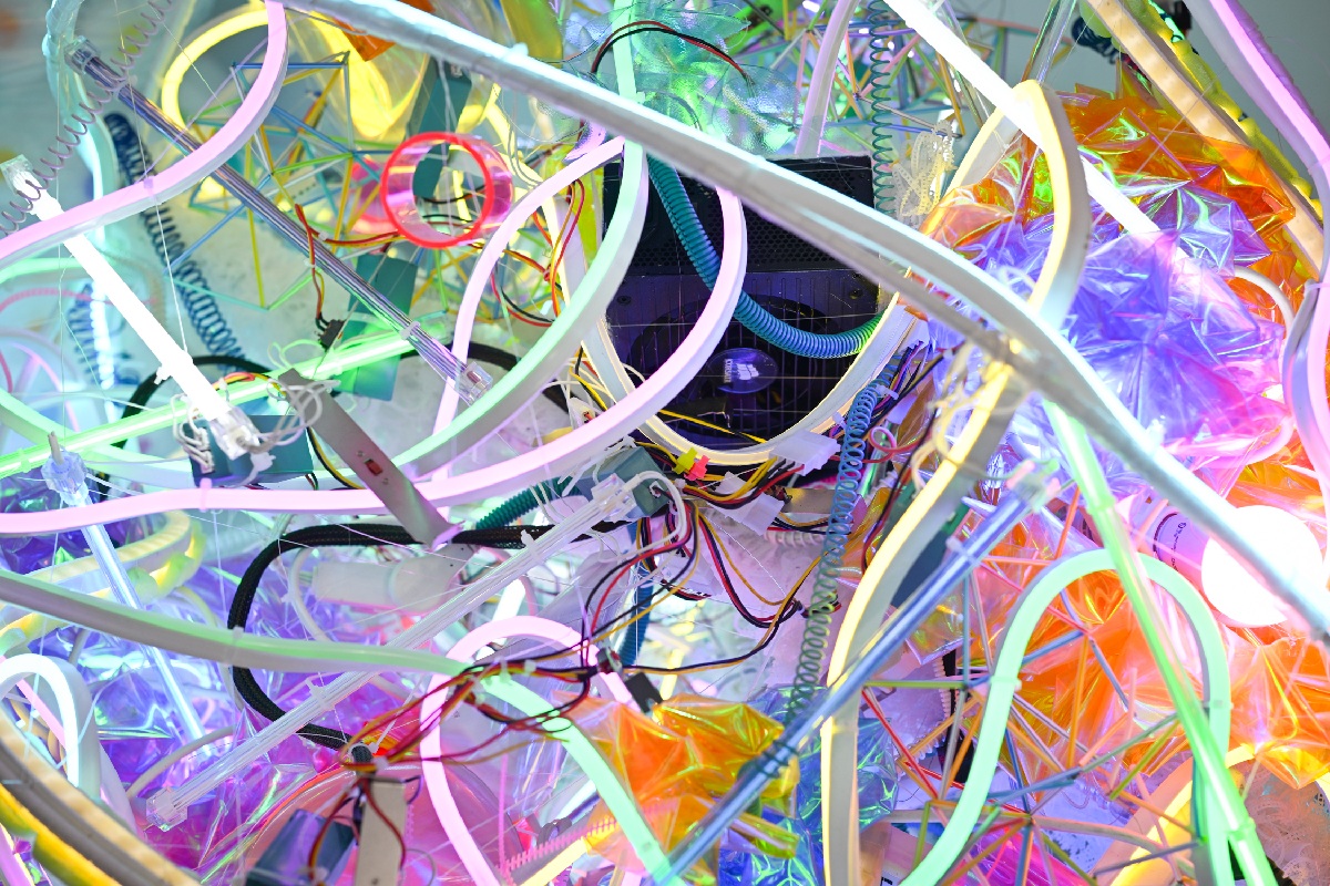 A cluster of neon rope lighting in multiple colors and a black box in the distance.