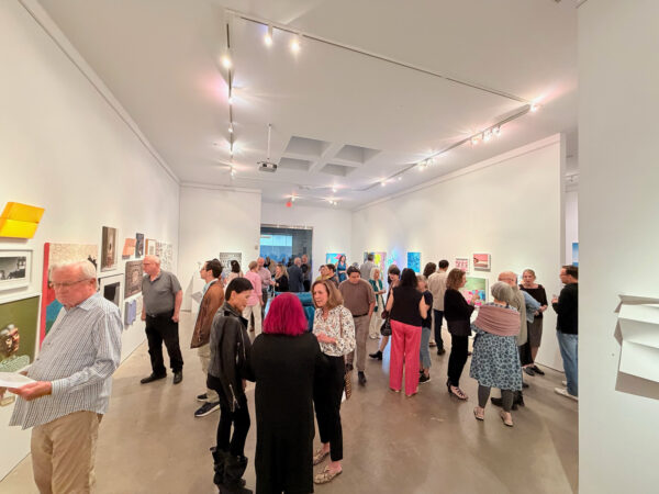 A photograph of people gathered at an opening reception for a gallery exhibition.